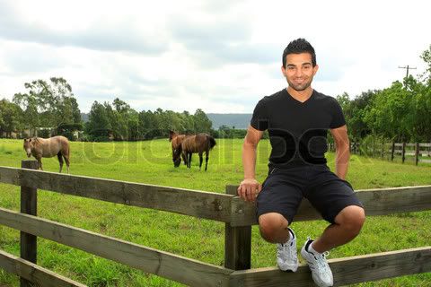 2836176-963284-a-smiling-happy-young-man-sitting-on-a-wooden-post-and-rail-fence-of-a-field-with-horses-grazing.jpg